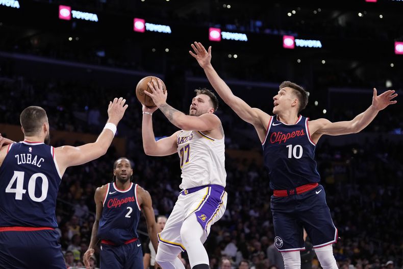 Luka Doncic (77), de los Lakers, se alista para tirar entre Ivica Zubac (40), Kawhi Leonard (2) y guard Bogdan Bogdanovic (10) de los Clippers de Los Ángeles, durante la segunda mitad del juego de baloncesto de la NBA, el domingo 2 de marzo de 2025, en Los Ángeles. (AP Foto/Mark J. Terrill)