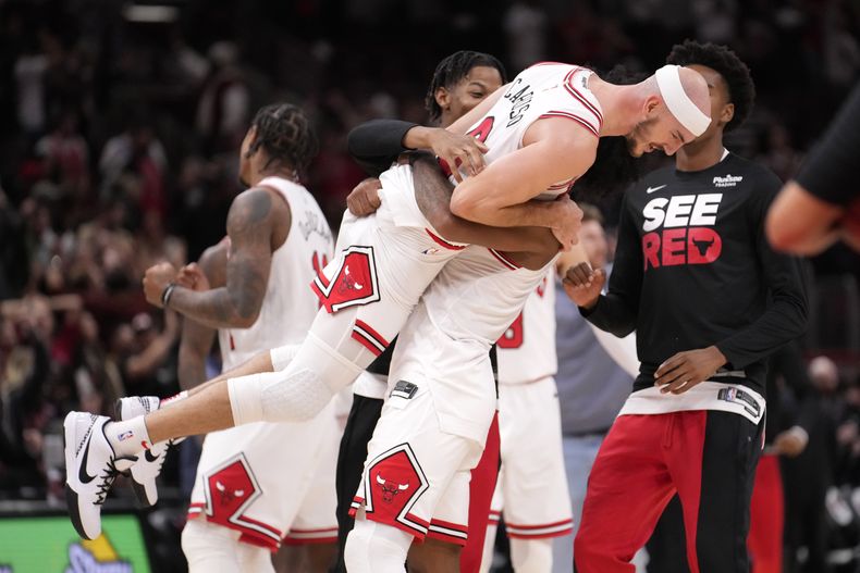 Alex Caruso, de los Bulls de Chicago, festeja con Coby White, tras la victoria en tiempo extra sobre los Raptors de Toronto, el viernes 27 de octubre de 2023 (AP Foto/Charles Rex Arbogast)