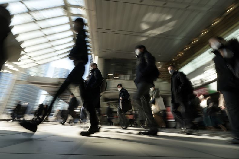ARCHIVO - Trabajadores usan mascarillas mientras se dirigen a sus lugares de trabajo durante la hora pico, el 8 de enero de 2021 en Tokio. (AP Foto/Eugene Hoshiko, archivo)