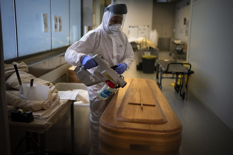 ARCHIVO - Un trabajador de una funeraria desinfecta un ataúd con el cuerpo de una persona que falleció a causa del COVID-19 antes de un funeral en el tanatorio Memora, en Girona, España, el 4 de febrero de 2021. (AP Foto/Emilio Morenatti, archivo)