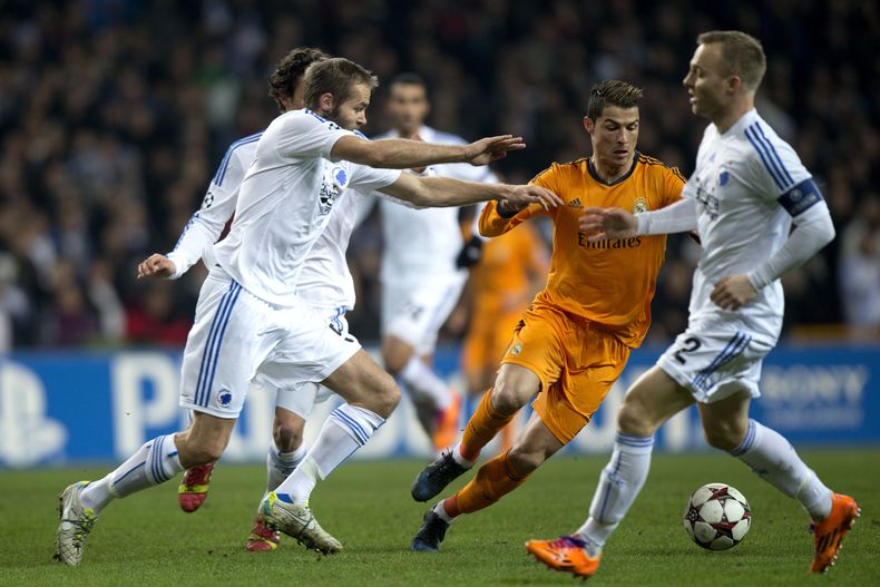 Cristiano Ronaldo, del Real Madrid, de naranja, conduce el bal&oacute;n entre jugadores del Copenhague durante un partido del Grupo B de la Liga de Campeones en el estadio Parken, en Copenhague, Dinamarca, el martes 10 de diciembre de 2013. (AP Foto/Polfo