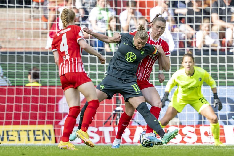 En foto del 18 de mayo del 2023, Alexandra Popp del Wolfsburg pelea por el balón con Samantha Steuerwald del Freiburg en el encuentro de liga. El viernes 2 de junio del 2023, el Wolfsburg se prepara para enfrentar el sábado en la final de la Liga de Campeones femenina al Barcelona en el estadio del PSV. (David Inderlied/dpa via AP)