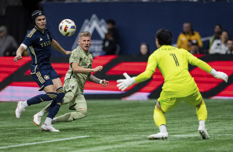 Mateusz Bogusz, centro, del LAFC, anota en contra de los Whitecaps de Vancouver, ante la mirada del portero Yohei Takaoka, derecha, y el defensa Bjorn Inge Utvik, izquierda, durante el primer tiempo del juego de fútbol de la MLS en Vancouver, Columbia Británica, el domingo 13 de octubre de 2024. (Ethan Cairns/The Canadian Press vía AP)