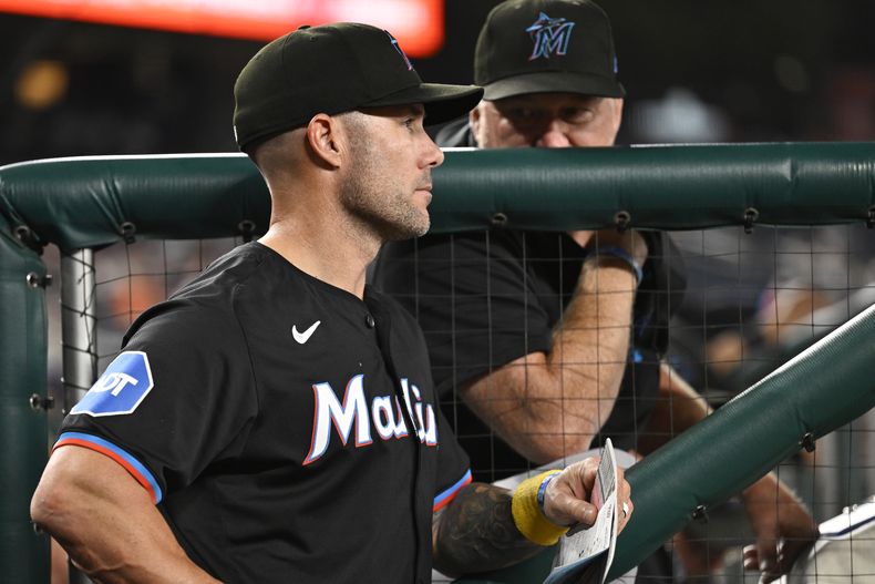 El mánager de los Marlins de Miami Skip Schumaker escucha al entrenador de pitchers Mel Sotttlemyre en el encuentro ante los Nacionales de Washington el jueves 12 de septiembre del 2024. (AP Foto/John McDonnell)