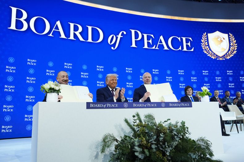 El presidente estadounidense Donald Trump (cent) aplaude mientras el presidente azerbaiyano Ilham Aliyev (izq) y el primer ministro búlgaro Rossen Jeliazkov (der) sujetan su acuerdo de la Junta de Paz en el Foro Mundial de Davos en Suiza, el 22 de enero del 2026. (AP foto/Evan Vucci)