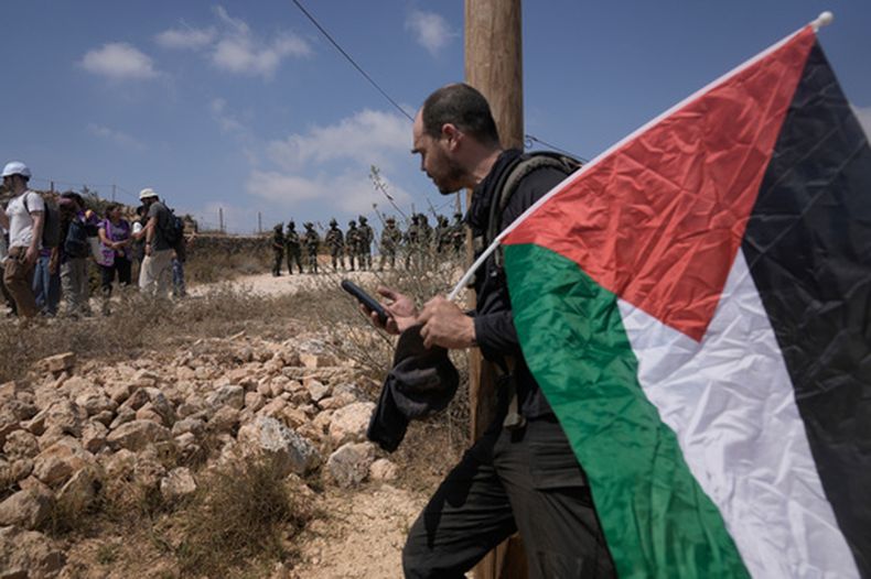 Soldados del ejército israelí hacen retroceder a activistas que marchaban con alimentos y agua hacia las casas de tres familias palestinas a las que colonos israelíes han mantenido sitiadas durante seis días, en el poblado de Qusra, en el sur de Naplusa, en Cisjordania, el viernes 14 de agosto de 2026. (AP Foto/Majdi Mohammed)