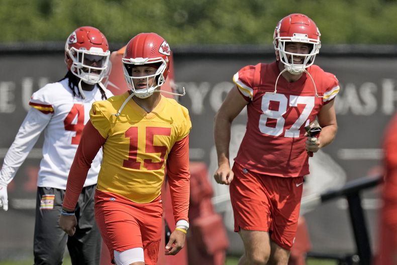 Patrick Mahomes (15), quarterback de los Chiefs de Kansas City, y el tight end Travis Kelce (87) calientan durante una actividad voluntaria organizada por el equipo, el miércoles 24 de mayo de 2023, en Kansas City, Missouri. (AP Foto/Charlie Riedel)