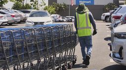 ARCHIVO - Un empleado recolecta carritos para compras vacíos del estacionamiento de una tienda de la cadena Walmart en Burbank, California, el jueves 10 de abril de 2025. (AP Foto/Damian Dovarganes, archivo)