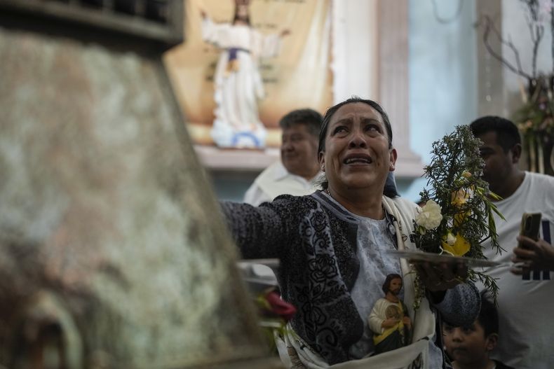 Una mujer toca una urna que contiene la reliquia de San Judas Tadeo durante su visita a la iglesia de San Cristóbal Mártir como parte de una gira nacional en San Cristóbal Texcalucan, México, el miércoles 7 de agosto de 2024.. (AP Foto/Eduardo Verdugo)