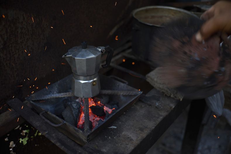 Edinector Vázquez aviva un fuego al carbón en el que prepara café durante un apagón en Minas, La Habana, Cuba, el lunes 26 de mayo de 2025. (AP Foto/Ramón Espinosa)