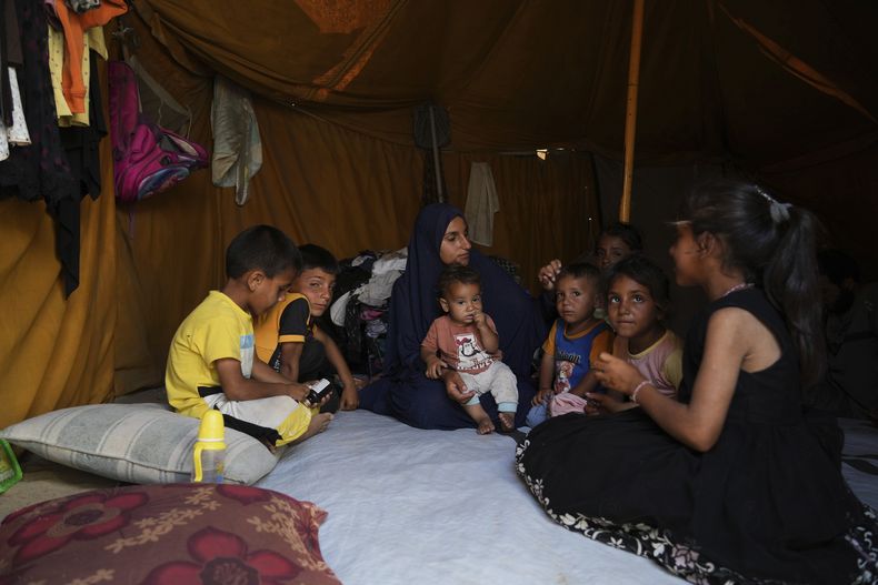 Maryam Abu Shaar, de 29 años, permanece junto con sus hijos dentro de su tienda en un campamento para palestinos desplazados, el viernes 6 de junio de 2025, en Mawasi Jan Yunis, Franja de Gaza. (AP Foto/Abdel Kareem Hana)