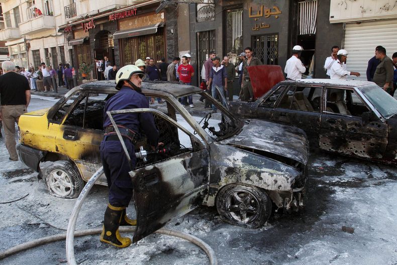 Los bomberos apagan un veh&iacute;culo incendiado despu&eacute;s que dos proyectiles de mortero hicieron impacto en la zona Abu Roumaneh de Damasco, Siria, el s&aacute;bado 12 de octubre de 2013. La agencia estatal de noticias siria inform&oacute; que los