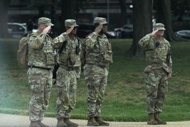 Soldados de la Guardia Nacional saludan al paso del vehículo del presidente Donald Trump cerca de la Casa Blanca, el jueves 21 de agosto de 2025, en Washington. (AP Foto/Jacquelyn Martin)
