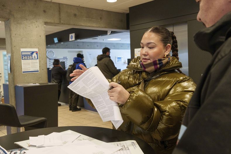 Una mujer lee su boleta antes de depositar el voto anticipado en las elecciones parlamentarias en Groenlandia, en la municipalía de Nuuk, Groenlandia, el 10 de marzo de 2025. (AP Foto/Evgeniy Maloletka)