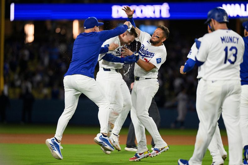 Dalton Rushing, centro, de los Dodgers de Los Ángeles, celebra su sencillo decisivo con Kike Hernandez, izquierda, y Miguel Rojas durante la undéxima entrada del juego de béisbol de Grandes Ligas contra los Rockies de Colorado, el lunes 6 de julio de 2026, en Los Ángeles. (AP Foto/Kyusung Gong)