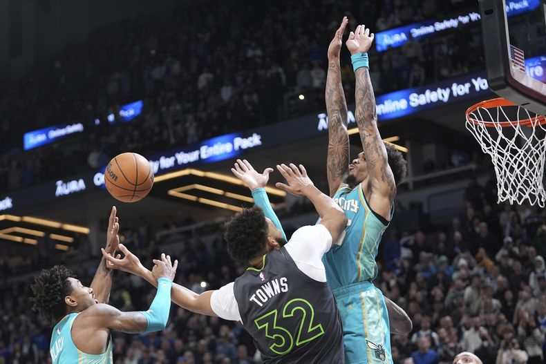 Karl-Anthony Towns (32), de los Timberwolves de Minnesota, pierde el control del balón mientras intentaba un tiro, con la presión defensiva de Leaky Black, izquierda, y P.J. Washington, de los Hornets de Charlotte, durante la segunda mitad del juego de baloncesto de la NBA, el lunes 22 de enero de 2024, en Minneapolis. (AP Foto/Abbie Parr)