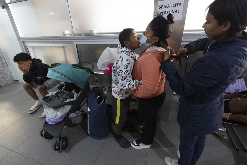 La venezolana Margelis Rodríguez, segunda por la derecha, recibe un abrazo de su hijo Mickel, de 12 años, mientras su amiga Ale la peina mientras esperan a que se haga la colada en una lavandería cerca del refugio migrante donde se aloja la familia en Tijuana, México, el viernes 31 de enero de 2025. (AP Foto/Gregory Bull)