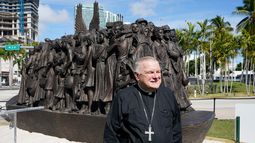 ARCHIVO - El arzobispo de Miami, Thomas Wenski, posa frente a una escultura itinerante de bronce titulada Ángeles desprevenidos, antes de bendecirla el 10 de febrero de 2021 en el centro de Miami. (Foto AP/Wilfredo Lee, archivo)