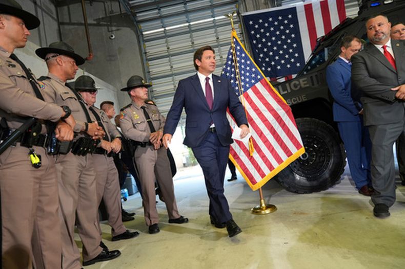 ARCHIVO - Agentes de la Patrulla de Caminos de Florida observan la llegada del gobernador Ron DeSantis a una conferencia de prensa sobre una reciente operación de control migratorio, en la oficina del Servicio de Inmigración y Control de Aduanas (ICE, por sus siglas en inglés) y la Oficina de Detención y Deportación (ERO por sus siglas en inglés), el 1 de mayo de 2025, en Miramar, Florida. (Foto AP/Rebecca Blackwell, archivo)