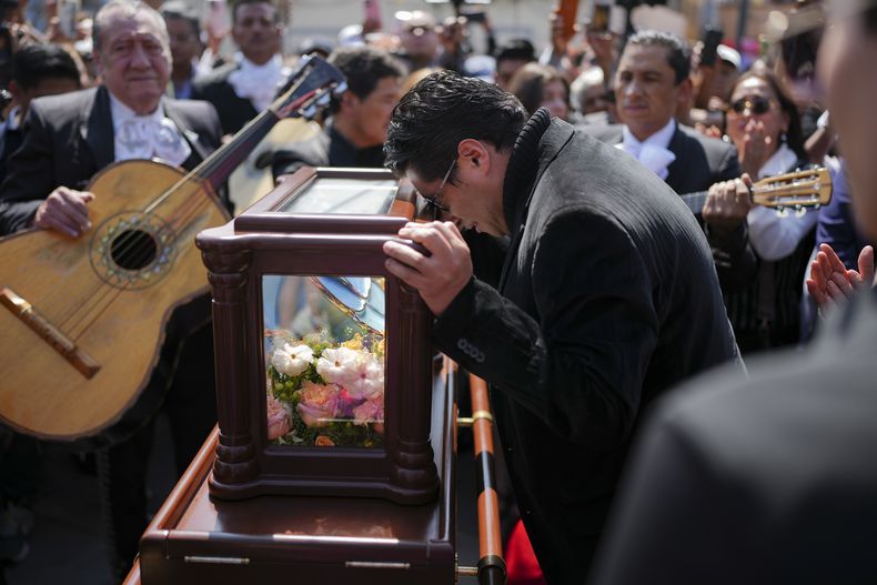Un amigo en duelo con la cabeza apoyada sobre la urna que contiene los restos de la leyenda mexicana de la música Paquita la del Barrio en un homenaje póstumo en la plaza Garibaldi, en Ciudad de México, el viernes 21 de febrero de 2025. (AP Foto/Eduardo Verdugo)