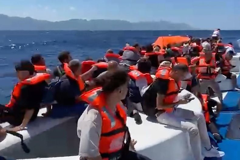 En esta imagen capturada de un video, pasajeros con chalecos salvavidas esperan sobre una embarcación de pasajeros volcada a ser rescatados frente a la costa de Girne, en la parte norte de Chipre ocupada por Turquía, el domingo 30 de agosto de 2026. (DHA vía AP)