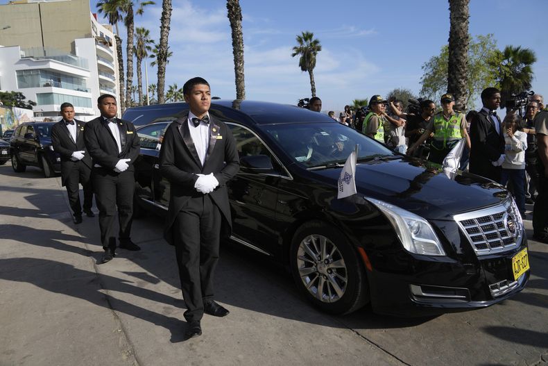 Varios trabajadores funerarios junto al vehículo con el ataúd del premio Nobel de Literatura peruano Mario Vargas Llosa rumbo a un crematorio en Lima, Perú, el lunes 14 de abril de 2025. (AP Foto/Martín Mejía)