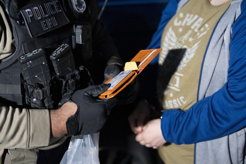 Agentes del Servicio de Control de Inmigración y Aduanas (ICE, por sus siglas en inglés) miran la identificación de una persona detenida, el lunes 27 de enero de 2025, en Silver Spring, Maryland. (AP Foto/Alex Brandon)