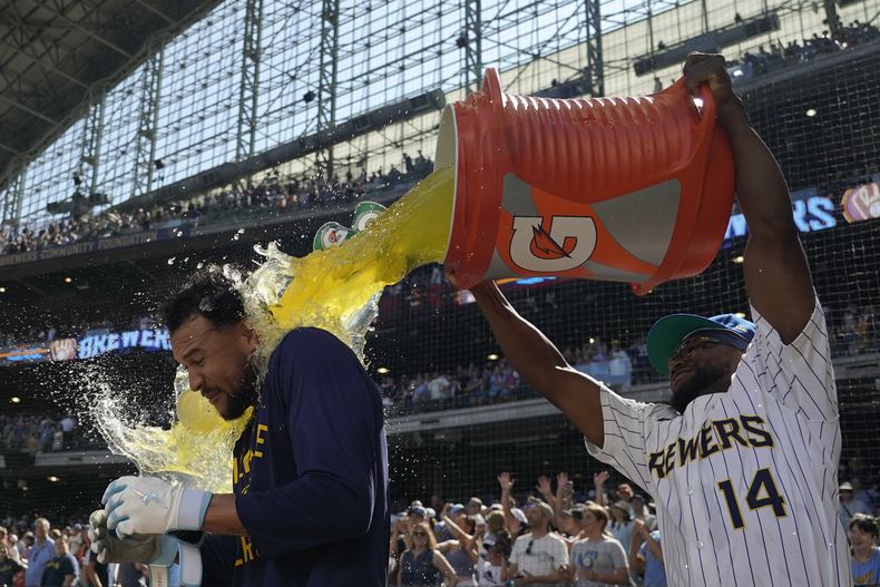 Blake Perkins, izquierda, de los Cerveceros de Milwaukee, recibe un baño por parte de Andruw Monasterio (14) después de batear el sencillo que impulsó la carrera decisiva en la novena entrada del juego de béisbol de Grandes Ligas frente a los Marlins de Miami, el domingo 27 de julio de 2025, en Milwaukee. (AP Foto/Aaron Gash)