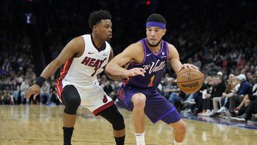 El armador de los Suns de Phoenix Devin Booker (derecha) conduce ante el base del Heat de Miami Kyle Lowry (izquierda), durante la primera mitad del juego de baloncesto de la NBA, el viernes 5 de enero de 2024, en Phoenix. (AP Foto/Rick Scuteri)