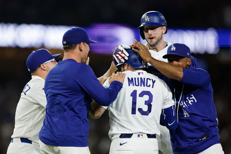 Max Muncy, de los Dodgers de Los Ángeles, es felicitado por sus compañeros luego de poner fin al duelo ante los Reales de Kansas City con un sencillo productor en la décima entrada, el martes 11 de agosto de 2026 (AP Foto/Caroline Brehman)