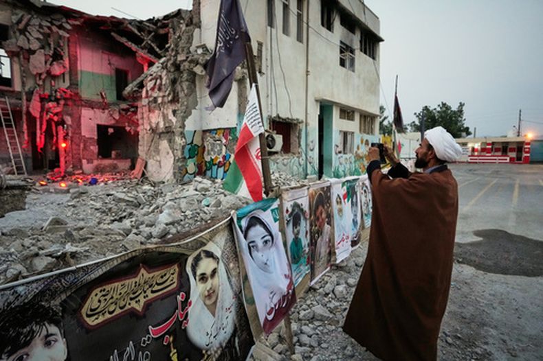 Un clérigo toma una foto en la destrozada escuela Shajareh Tayyebeh, que se ha convertido en un lugar de duelo y recuerdo de los fallecidos en un ataque aéreo estadounidense el 28 de febrero, en Minab, en el sur de Irán, el 7 de septiembre de 2026. (AP Foto/Vahid Salemi)