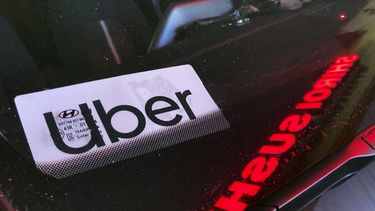 ARCHIVO - Un cartel de Uber en un auto en Glenview, Illinois, EEUU, 17 de diciembre de 2022. Las empresas de taxis por internet Uber y Lyft pagarán en conjunto 328 millones de dólares para resolver un pleito judicial por robo de salarios en Nueva York, informó la procuradora estatal Letitia James el jueves 2 de noviembre de 2023. (AP Foto/Nam Y. Huh, File)