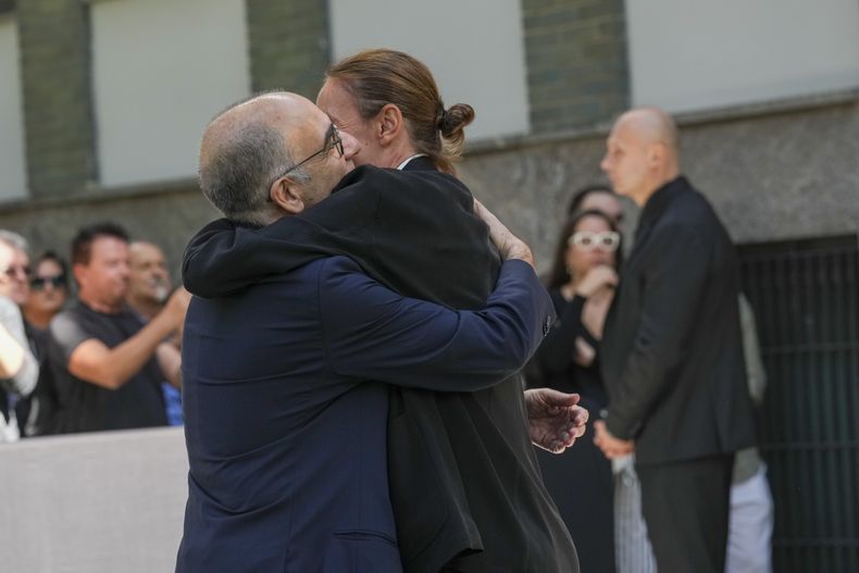El director de cine italiano Giuseppe Tornatore, a la izquierda, recibe un abrazo cuando llega para presentar sus respetos al diseñador de moda Giorgio Armani, quien yace en el Armani/Teatro en Milán, en el norte de Italia, el sábado 6 de septiembre de 2025. (Foto AP/Antonio Calanni)