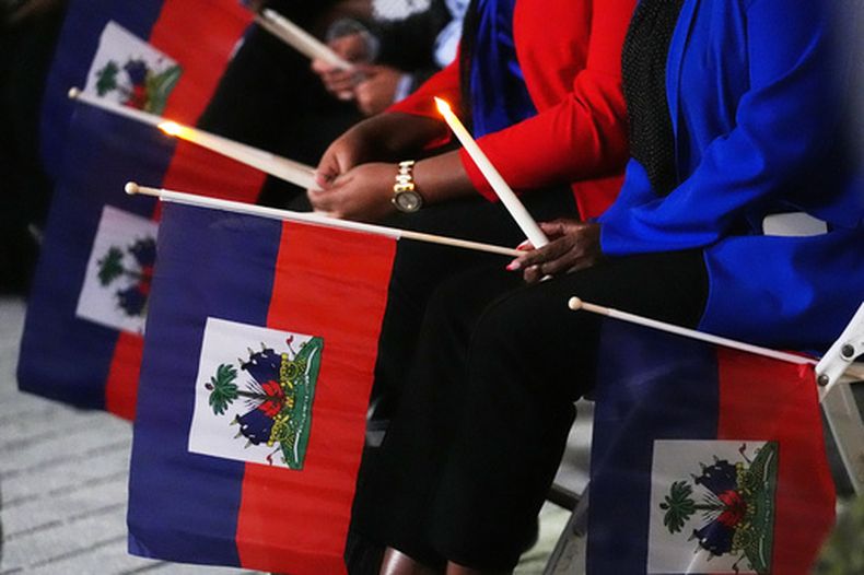 ARCHIVO - Varias personas sostienen banderas haitianas y velas durante una vigilia en el Complejo Cultural Pequeño Haití luego de que un juez federal impidiera que el gobierno del presidente Donald Trump pusiera fin al Estatus de Protección Temporal (TPS) para los haitianos, el 3 de febrero de 2026, en North Miami. (AP Foto/Lynne Sladky, archivo)