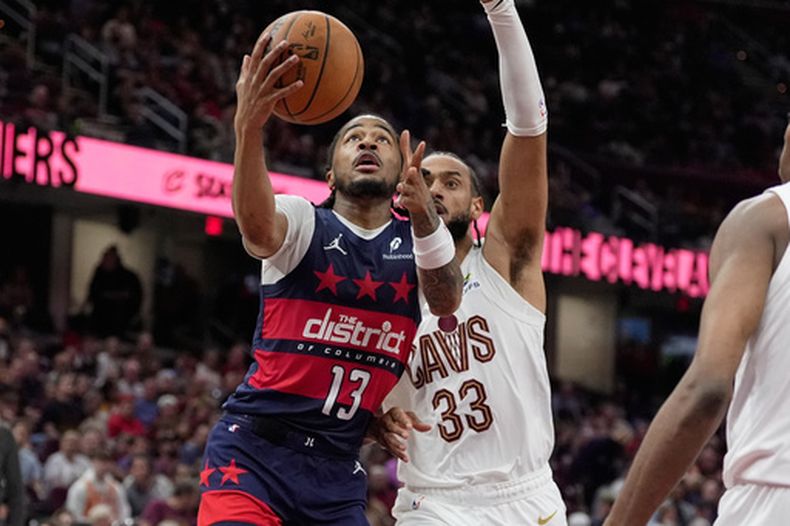 El base de los Wizards de Washington, Sharife Cooper (13), se dirige a la canasta superando al delantero de los Cavaliers de Cleveland, Olivier Sarr (33), en la segunda mitad de un partido de baloncesto de la NBA en Cleveland, el domingo 12 de abril de 2026. (AP Foto/Sue Ogrocki)