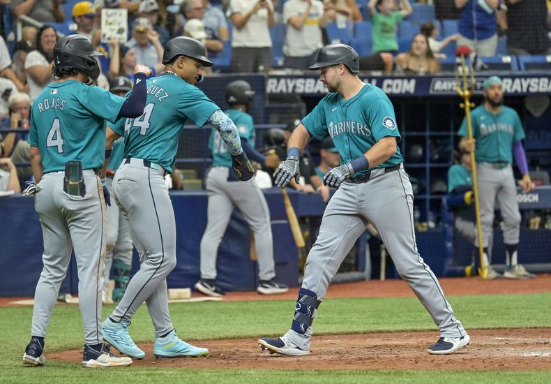El tercera base de los Marineros de Seattle Josh Rojas y el dominicano Julio Rodríguez felicitan a Cal Raleigh tras su jonrón de tres carreras frente a los Rays de Tampa Bay el miércoles 26 de junio del 2024. (AP Foto/Steve Nesius)