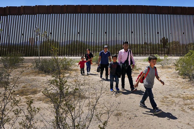 Una familia de cinco personas que dijo ser de Guatemala y un hombre que viaja con ellos que afirma es oriundo de Perú, de camisa rosa, caminan por el desierto tras cruzar el muro fronterizo en el Sector de Tucson de la frontera Estados Unidos-México, el martes 29 de agosto de 2023, en el Monumento Nacional Organ Pipe Cactus cerca de Lukeville, Arizona. (AP Foto/Matt York)