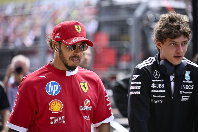 Lewis Hamilton, izquierda, piloto británido de Ferrari, llega para el desfile de pilotos en el circuito Hungaroring, en Mogyorod, Hungría, el domingo 3 de agosto de 2025, previo al Gran Premio de Hungría de F1. (AP Foto/Denes Erdos)