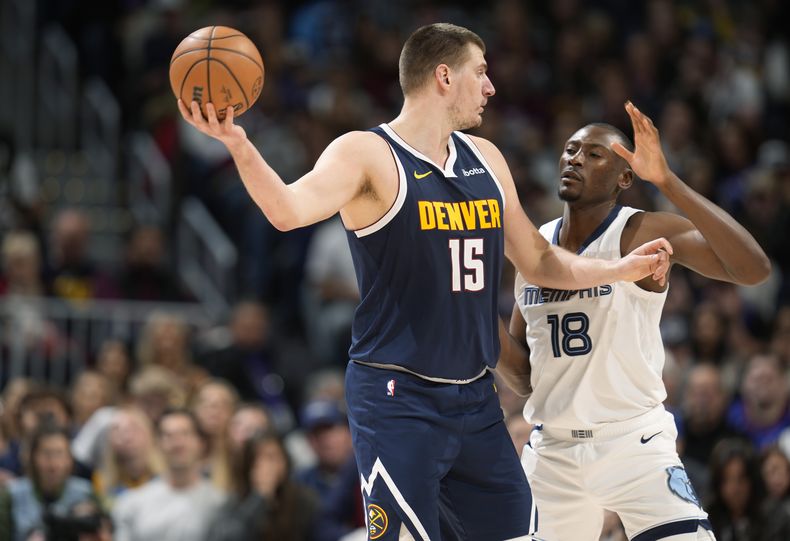 El serbio Nikola Jokic busca enviar un pase frente a Bismack Biyombo, de los Grizzlies de Memphis, en el partido del jueves 28 de diciembre de 2023 (AP Foto/David Zalubowski)