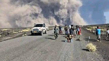 En esta foto publicada por la Oficina de Comunicación del Gobierno de Afar, un grupo de personas observa la columna de cenizas de una erupción del volcán Hayli Gubbi, inactivo desde hace mucho tiempo, en la región de Afar, Etiopía, el domingo 23 de noviembre de 2025. (Oficina de Comunicación del Gobierno de Afar vía AP)