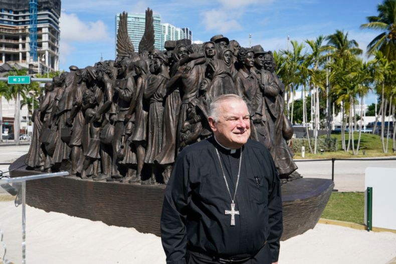 ARCHIVO - El arzobispo de Miami, Thomas Wenski, posa frente a una escultura itinerante de bronce titulada Ángeles desprevenidos, antes de bendecirla el 10 de febrero de 2021 en el centro de Miami. (Foto AP/Wilfredo Lee, archivo)