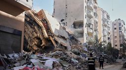 Miembros de Hezbollah caminan frente a un edificio destruido por un ataque aéreo israelí en Dahiyeh, en los suburbios del sur de Beirut, Líbano, el jueves 5 de marzo de 2026. (AP Foto/Hassan Ammar)