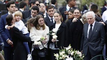 Miguel Uribe, a la derecha, y María Claudia Tarazona, con su hijo Alejandro en brazos, padre y esposa del aspirante presidencial y senador opositor Miguel Uribe, fallecido a causa de las heridas sufridas al recibir un disparo en un mitin político, se encuentran junto a otros familiares junto a su ataúd en el cementerio durante su funeral en Bogotá, Colombia, el miércoles 13 de agosto de 2025. (Foto AP/John Vizcaino)