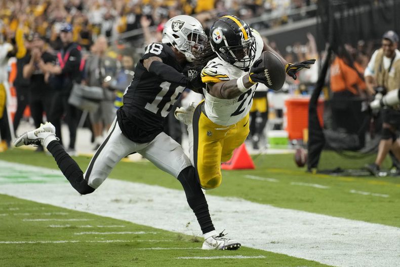 El corredor de los Steelers de Pittsburgh, Najee Harris, a la derecha, se lanza hacia la zona de anotación para superar al esquinero de los Raiders de Las Vegas, Jack Jones, durante la segunda mitad de un partido de fútbol americano de la NFL en Las Vegas, el domingo 13 de octubre de 2024. (AP Foto/John Locher)