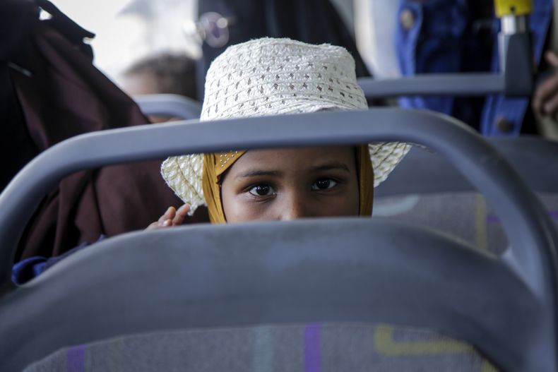 Somalíes que huyeron del conflicto en Sudán están sentados en un autobús después de regresar a casa en el aeropuerto de Mogadiscio, Somalia, el domingo 30 de abril de 2023. (AP Foto/Farah Abdi Warsameh)