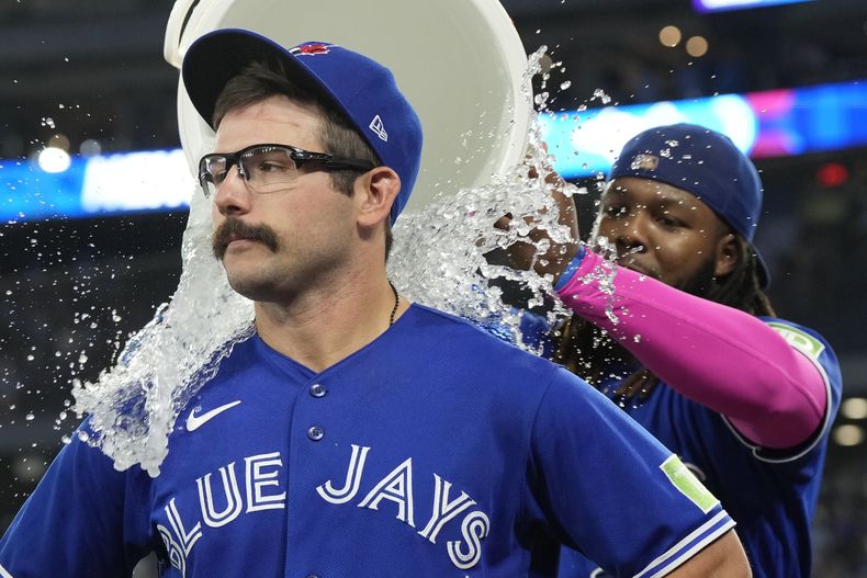 El dominicano Vladimir Guerrero Jr., de los Azulejos de Toronto, vacía la hielera encima de su compañero Davis Schneider, tras el triunfo sobre los Guardianes de Cleveland, el sábado 26 de agosto de 2023 (Frank Gunn/The Canadian Press via AP)