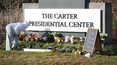 Christine Mason, de Atlanta, coloca flores a la entrada del Centro Presidencial Jimmy Carter el lunes 30 de diciembre de 2024, en Atlanta. El expresidente Carter falleció el domingo en su casa en Plains, Georgia, a la edad de 100 años. (AP Foto/John Bazemore)