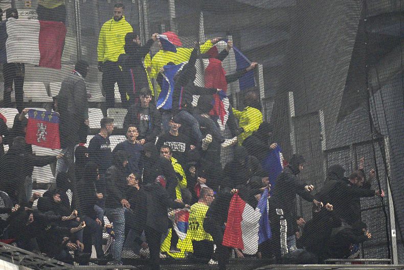 ARCHIVO - Hinchas de Lyon intentan romper la malla en las gradas previo al partido contra el Olympique de Marsella, el domingo 29 de octubre de 2023, en el estadio Velodrome de Marsella. (AP Foto/Daniel Cole)