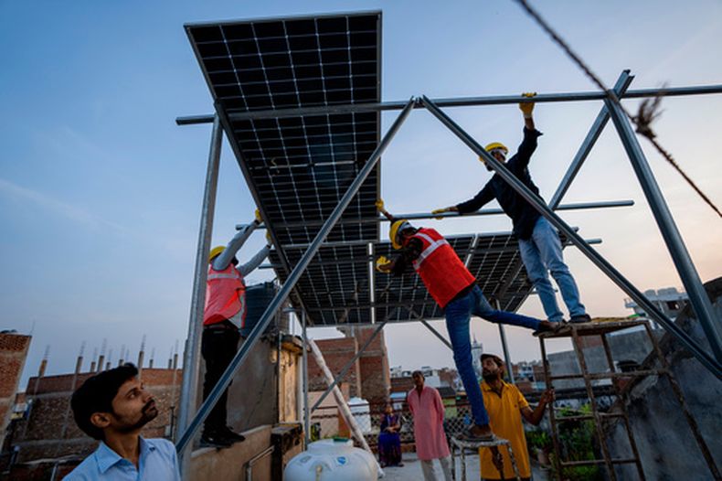 ARCHIVO – Varios trabajadores instalan paneles solares en el techo de una casa en Prayagraj, India, el lunes 14 de octubre de 2024. (AP Foto/Rajesh Kumar Singh, Archivo)
