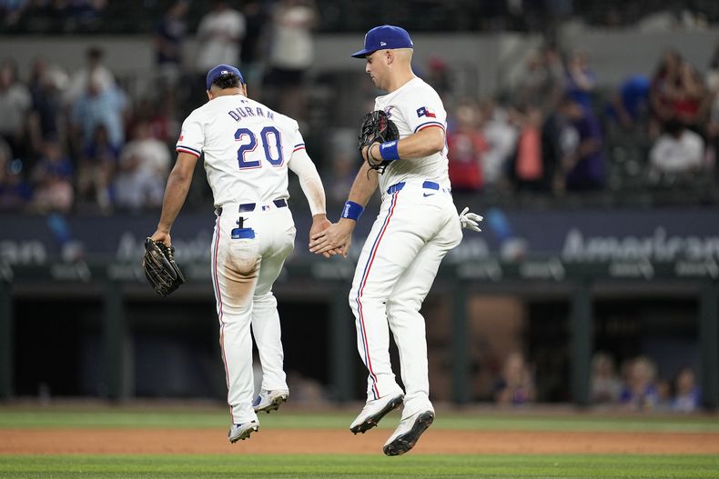 Ezequiel Durán (20) y Nathaniel Lowe, de los Rangers de Texas, celebran la victoria del equipo contra los Tigres de Detroit en un partido de béisbol el miércoles 5 de junio de 2024 en Arlington, Texas. (AP Foto/Tony Gutiérrez)